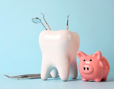 A piggy bank next to dental instruments along a blue background