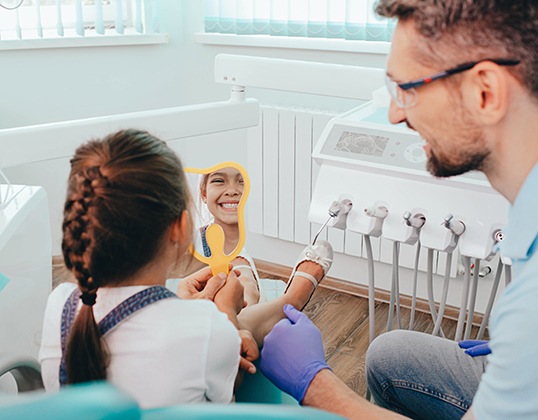 Little girl looking at her fully restored smile in the mirror