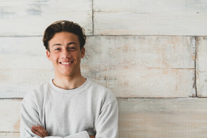 a teenager standing by a wall and smiling