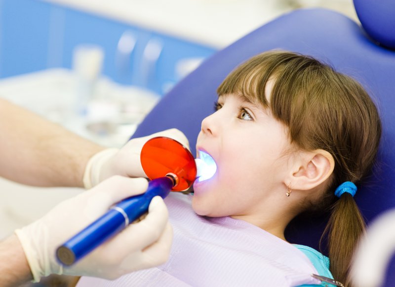 a little girl having a tooth filled while in dentist’s chair